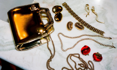 Ben-Amun earrings lay on white marble counter next to gold purse and holiday jewelry