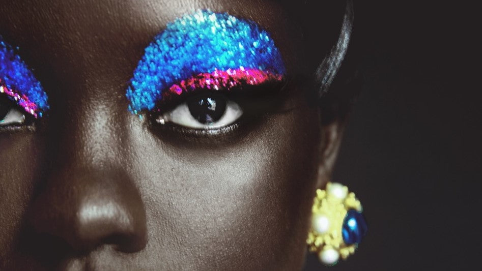 close-up of female model wearing gold clip-on earrings with navy stone