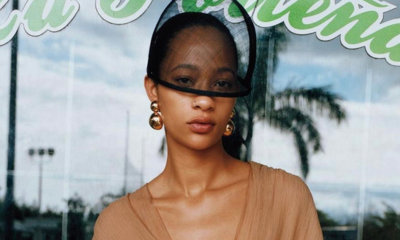 Model in black veil hat and gold ball Ben-Amun earrings poses in front of reflective wall