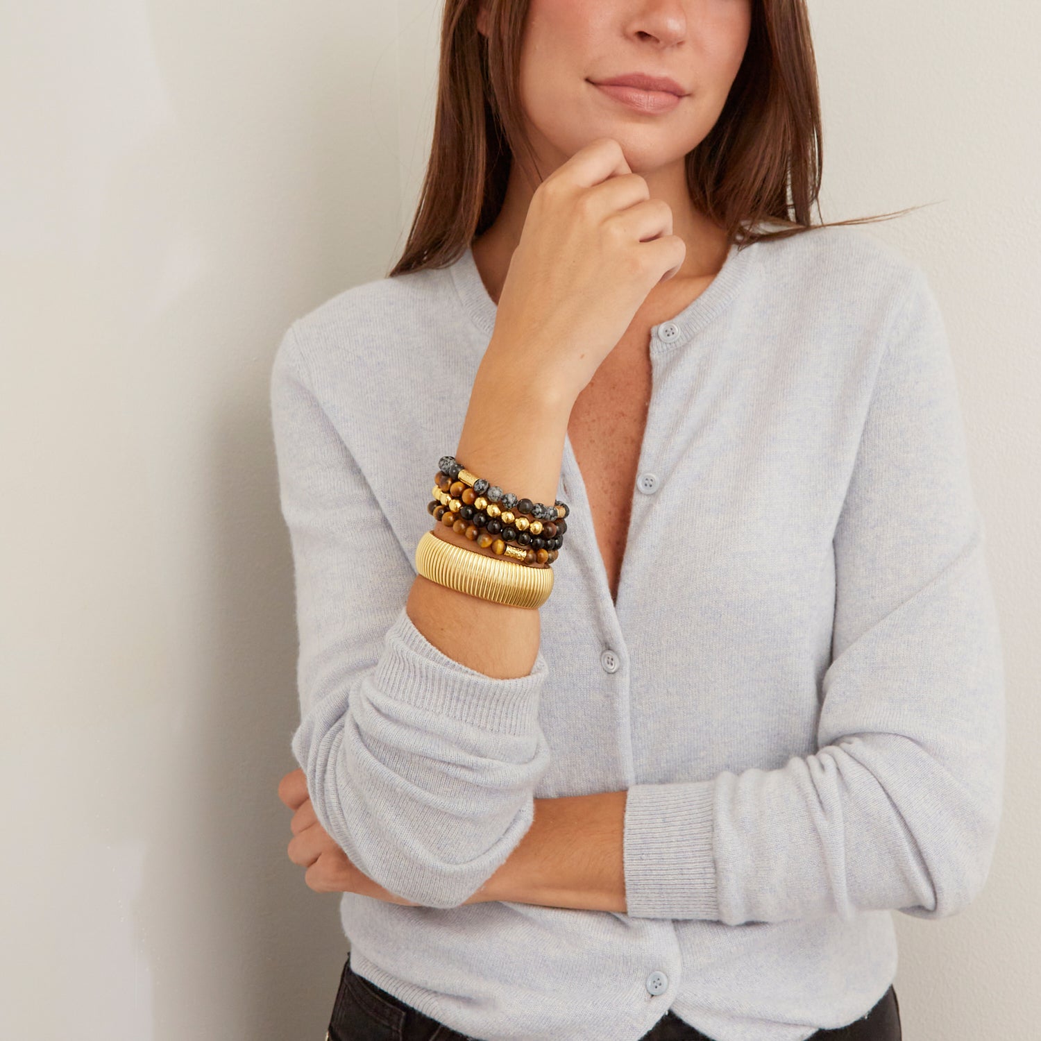 woman wearing large gold bangle and colorful beaded bracelets