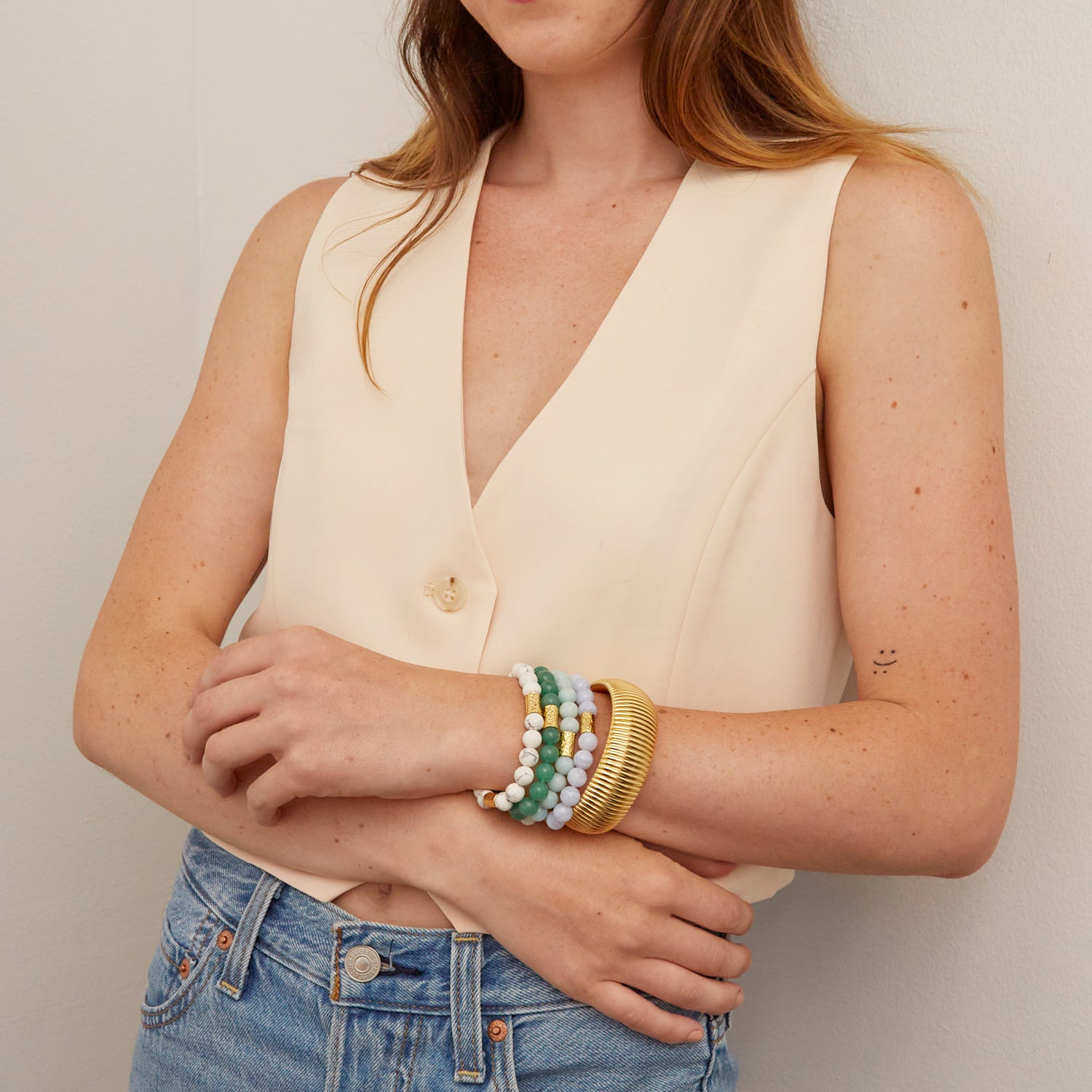 woman wearing gold bangles and colorful beaded bracelets