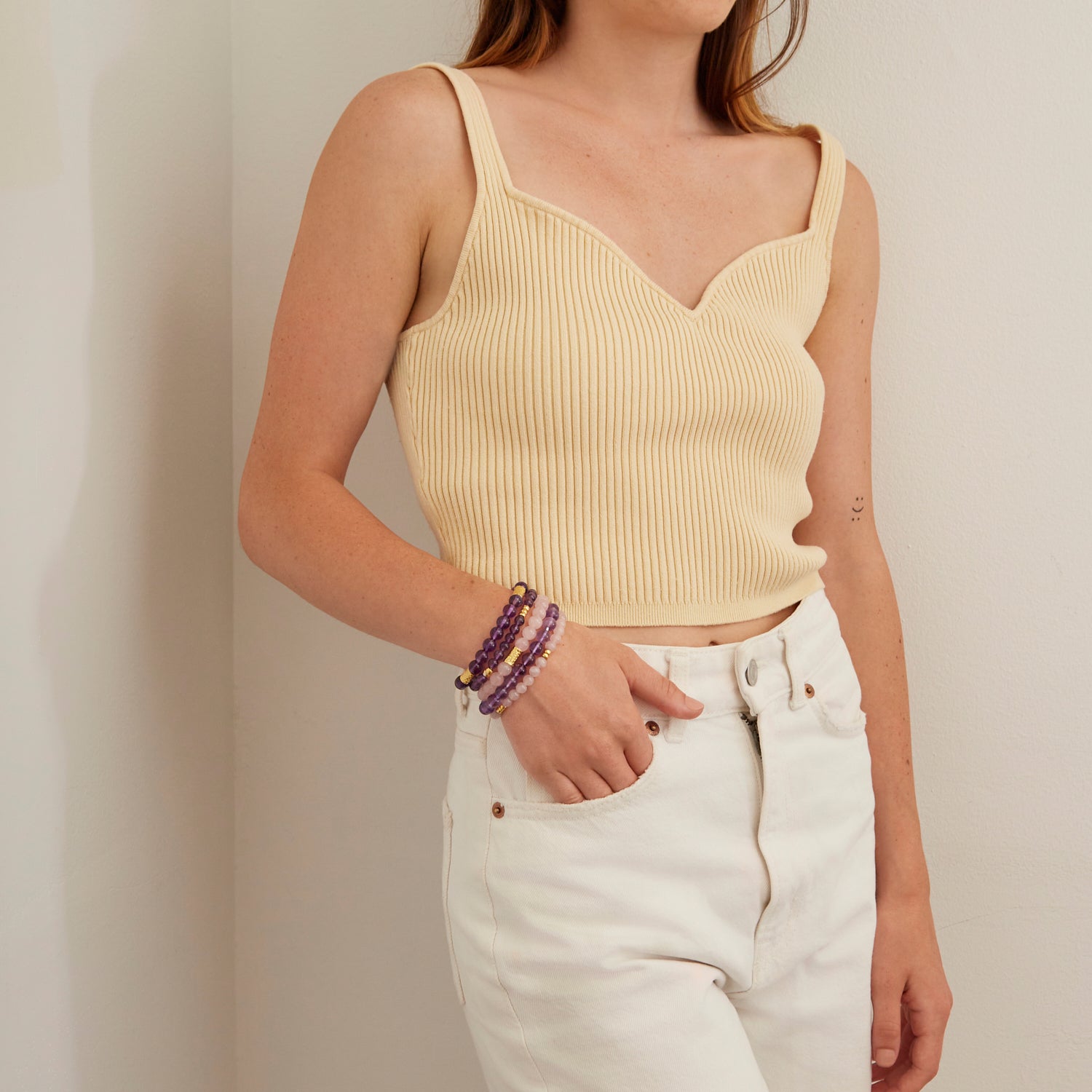 woman wearing light pink and purple stone bracelet with gold beads