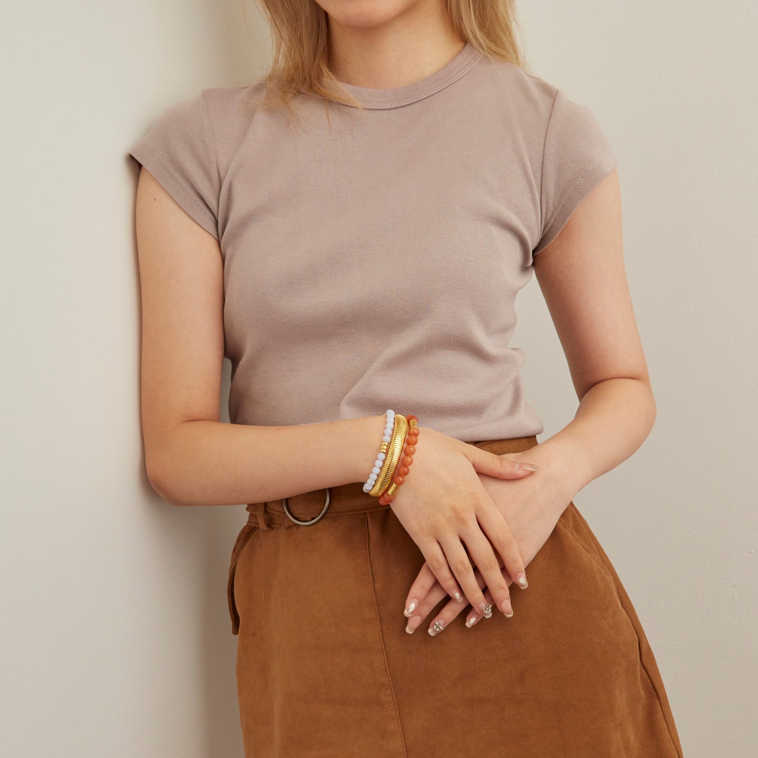 woman wearing gold bangle and blue and orange beaded bracelets