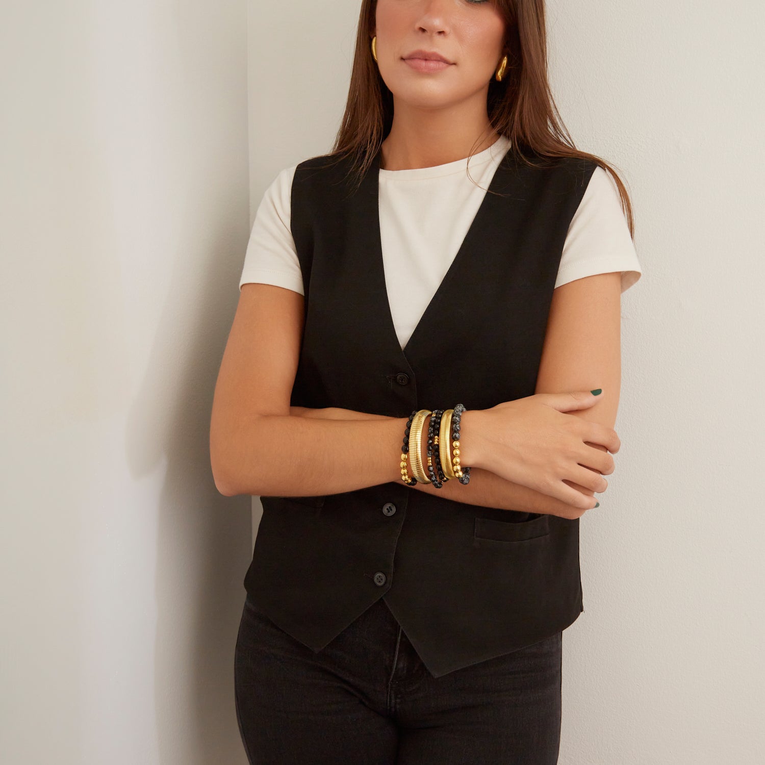 woman wearing gold bangles and black beaded bracelets