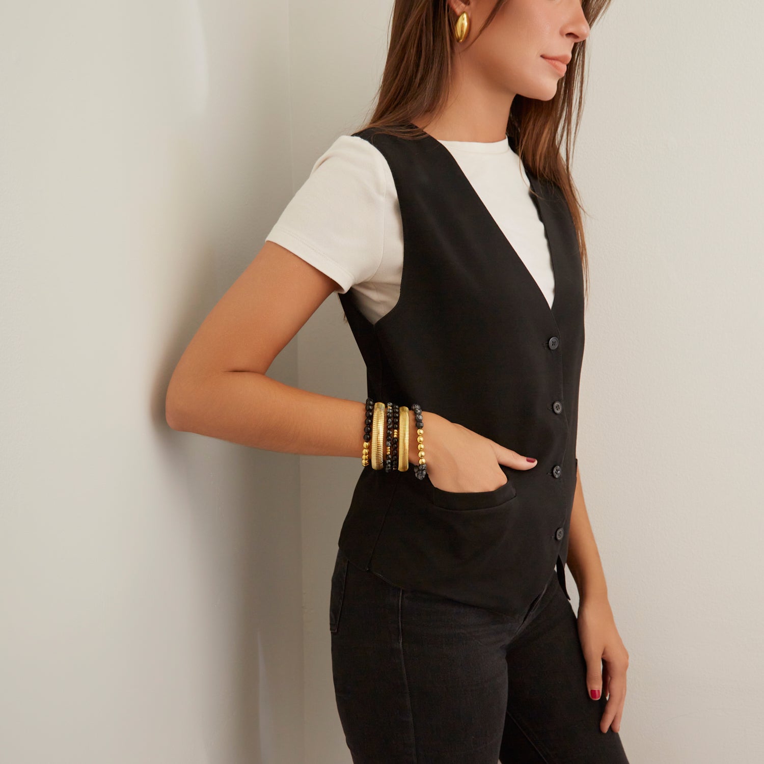 woman wearing gold bangles and black beaded bracelets