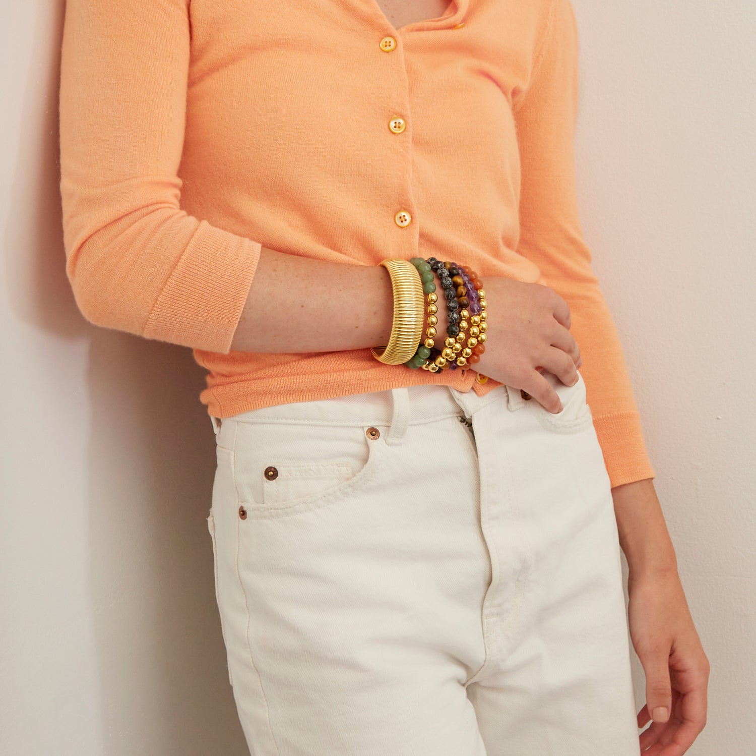 woman wearing gold bangle and colorful beaded bracelets