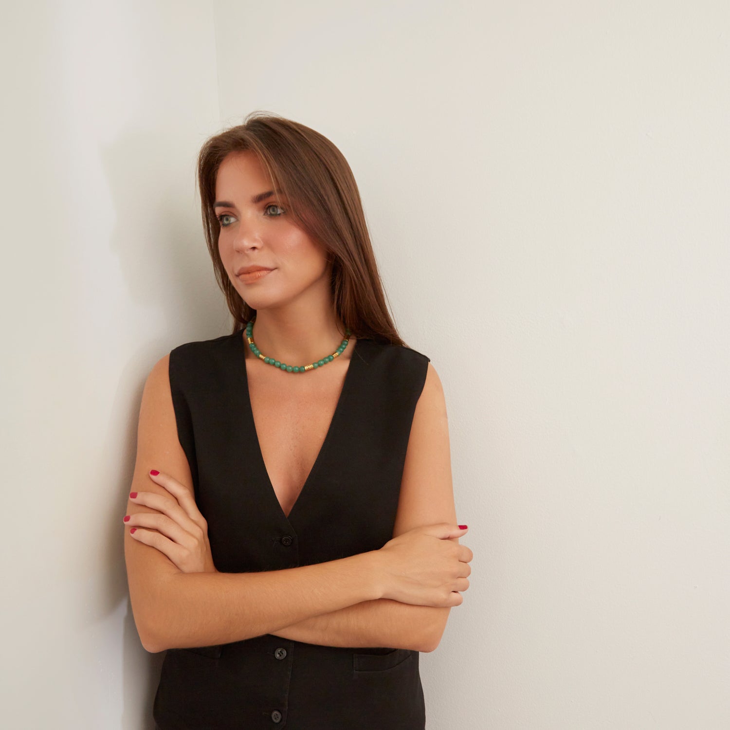 woman in black vest wearing jungle green stone necklace with gold beads