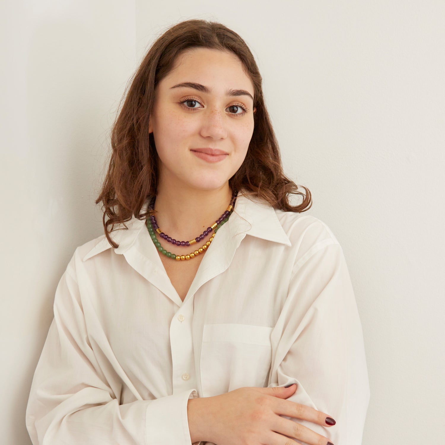 woman wearing green and purple stone necklaces with gold beads