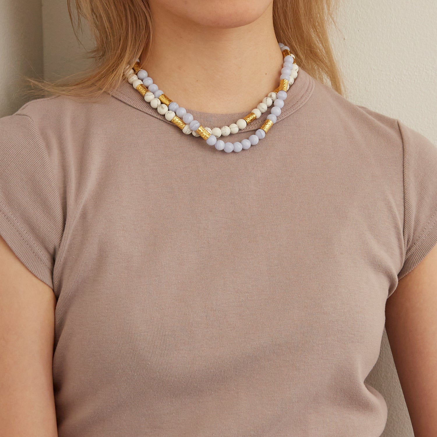 woman wearing gray shirt and two white marble stone necklaces with gold beads