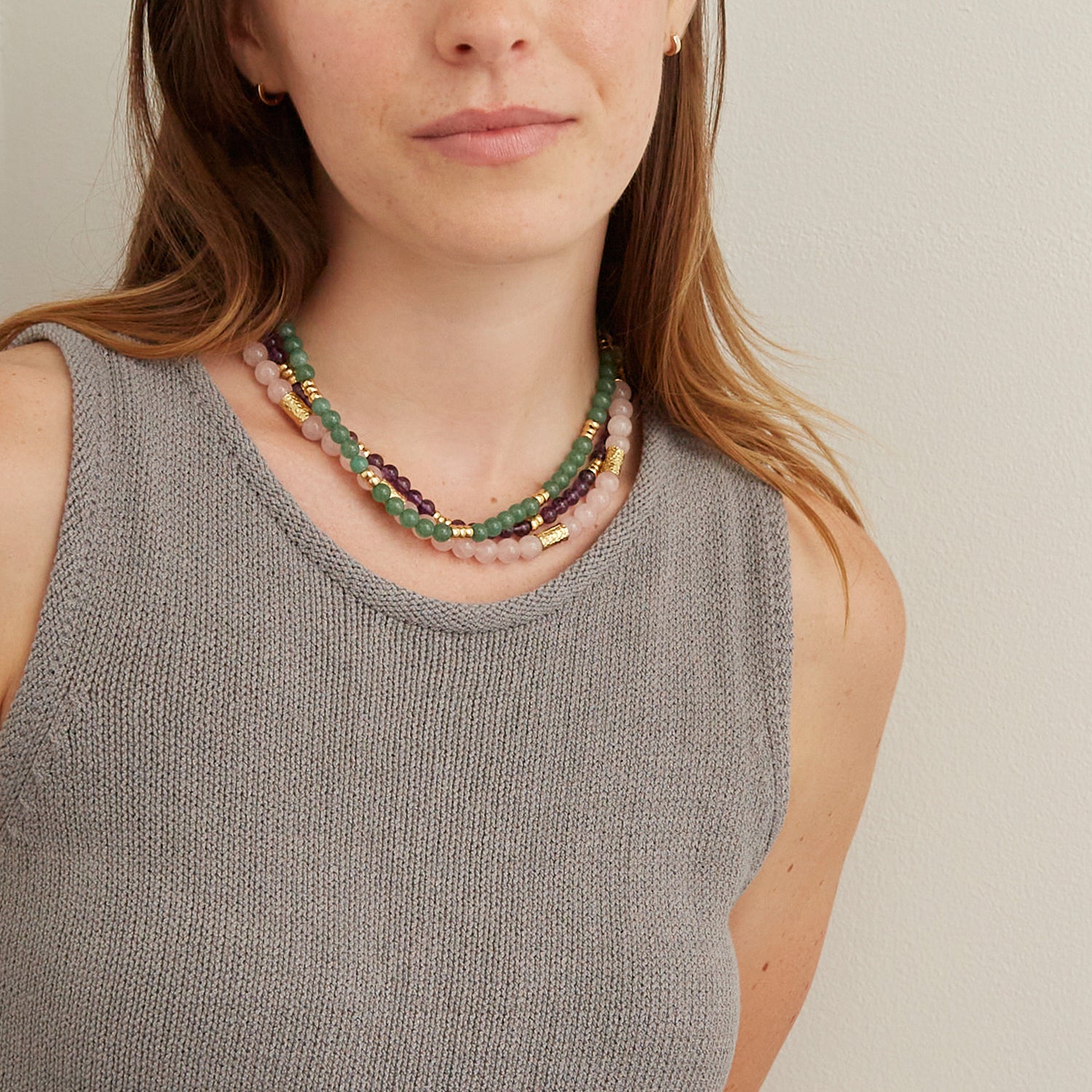 woman in gray tank top wearing light purple, pink and green beaded necklaces