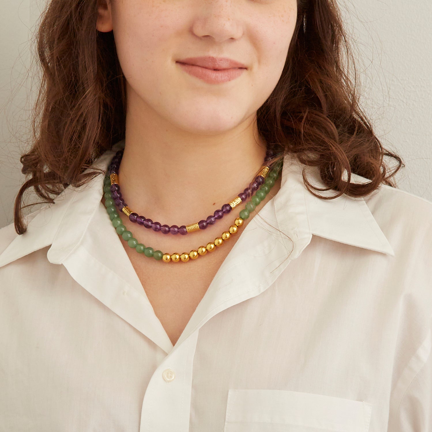 woman in white collared shirt wearing purple and green beaded necklace