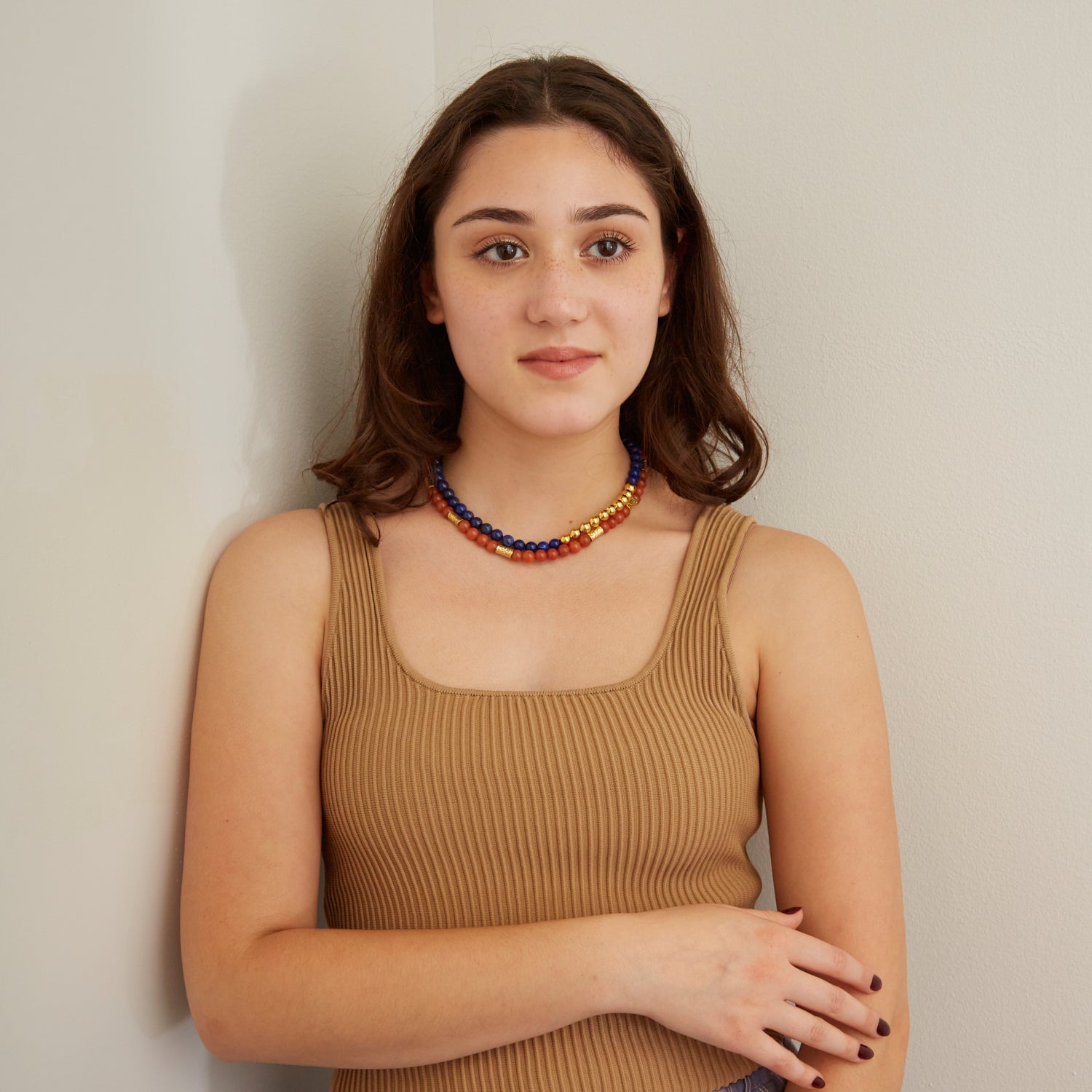 woman in tan tank top wearing blue and orange stone necklaces with gold beads