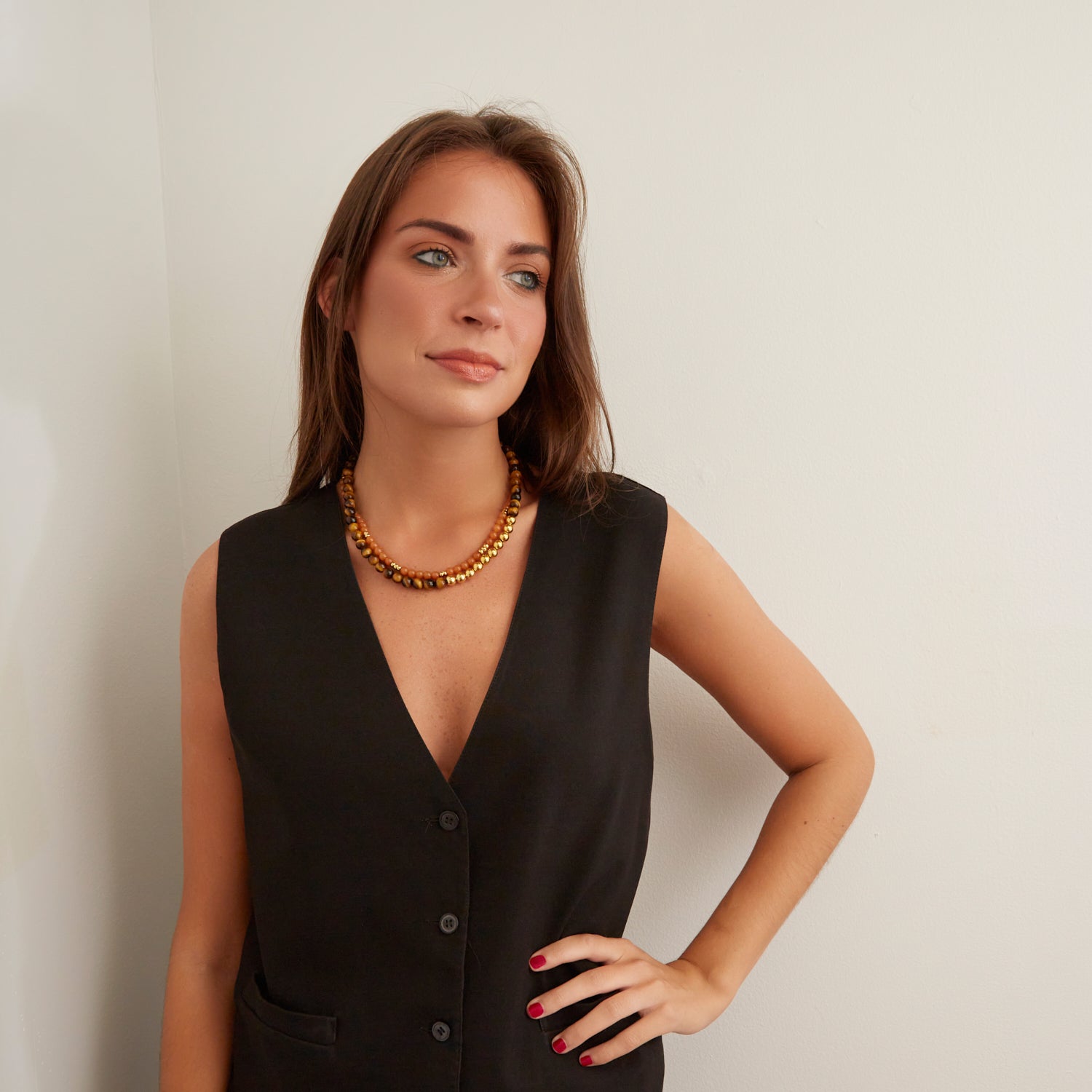 woman in black vest wearing brown and orange stone necklaces