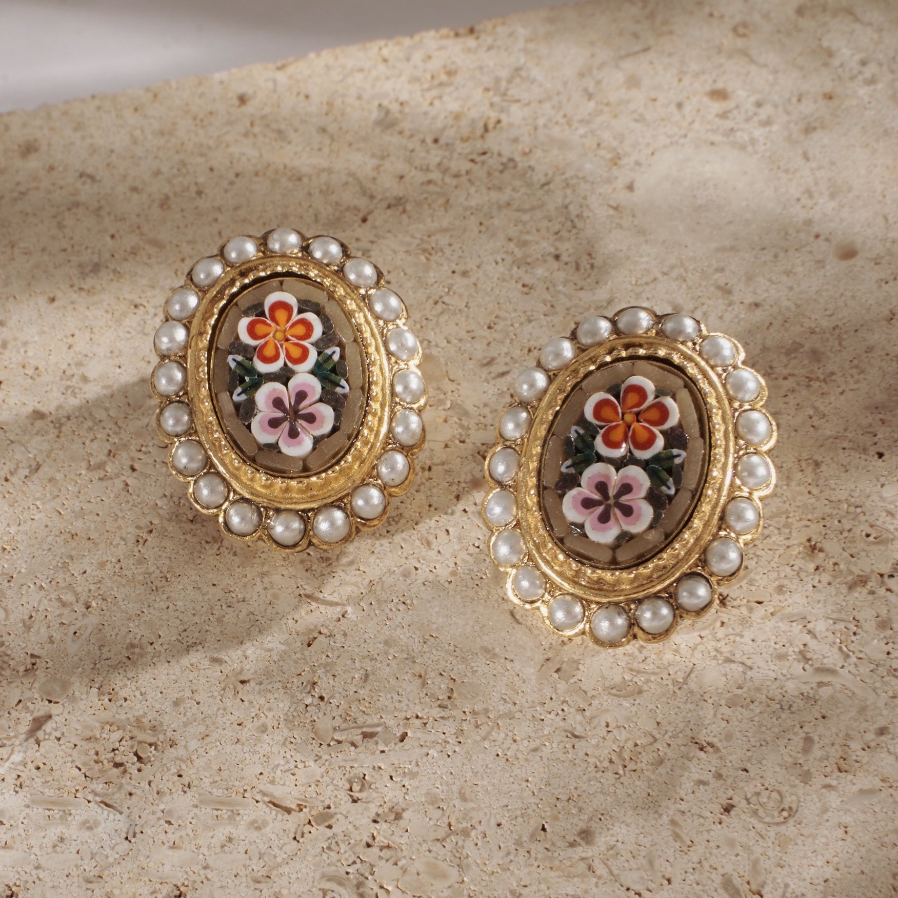 flatlay of Ben-Amun gold-plated clip-on earrings against stone background 