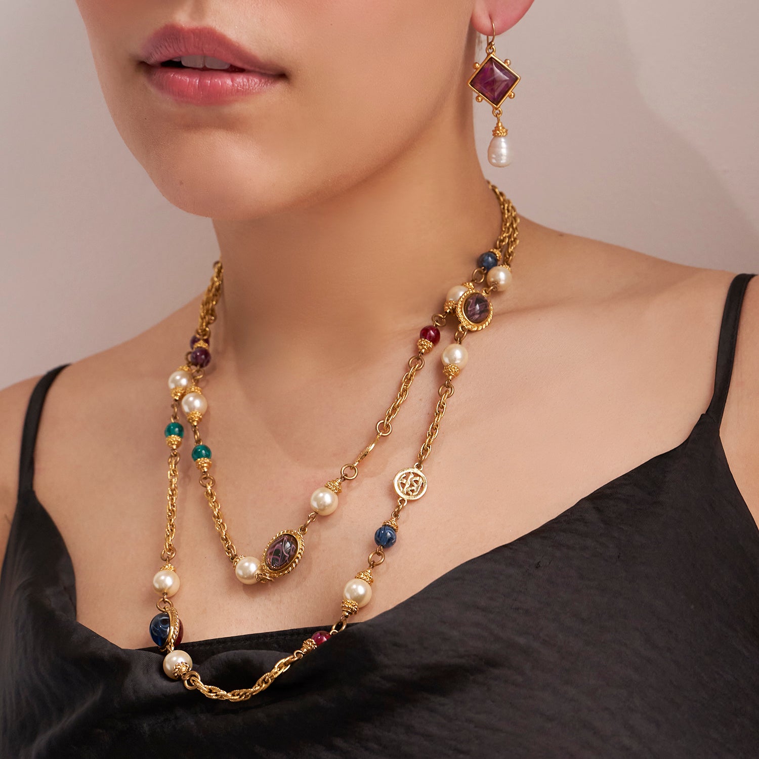 Model wearing gold fish hook earrings and gold necklace with gemstones 