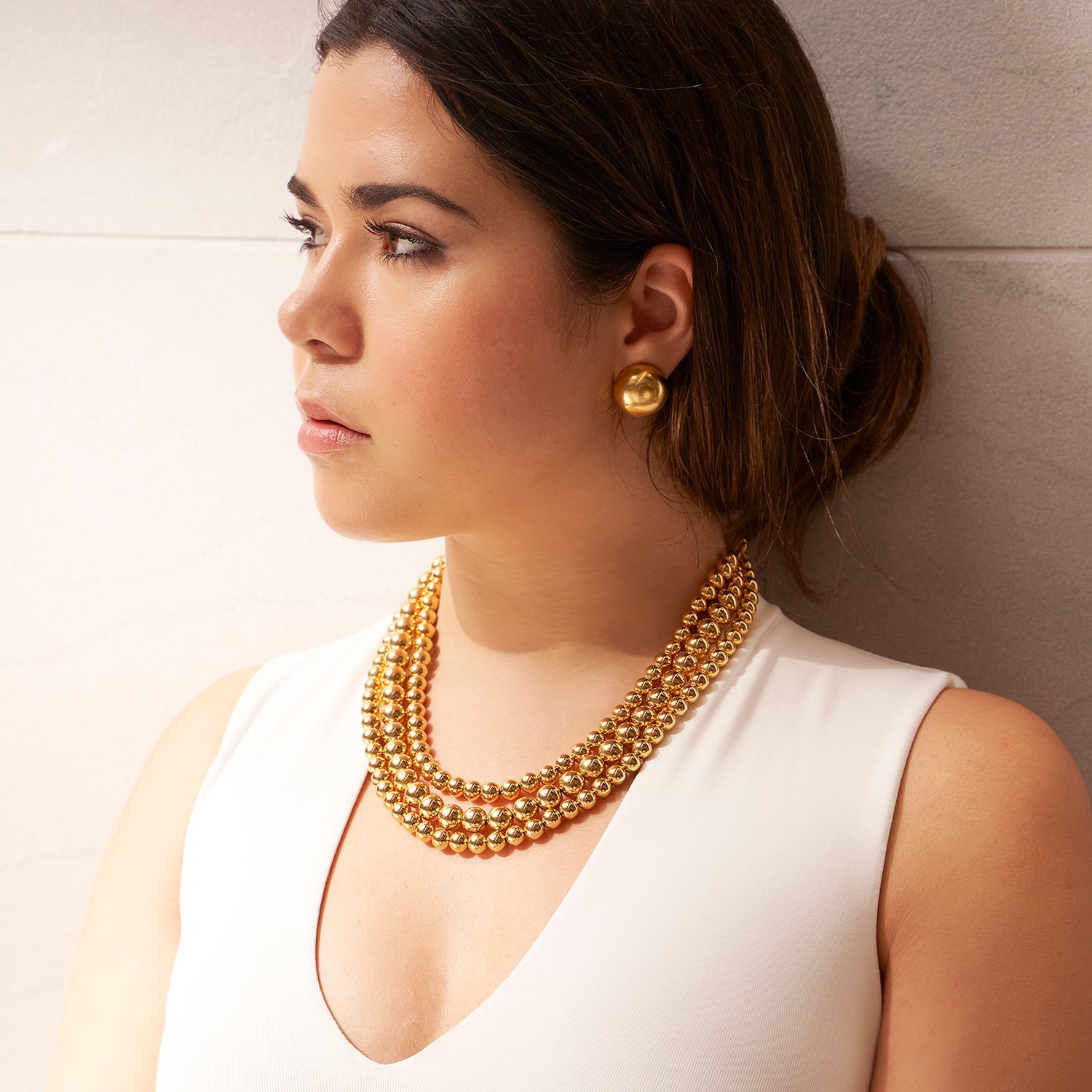 Model styled with three layer gold ball necklace and gold ball earrings