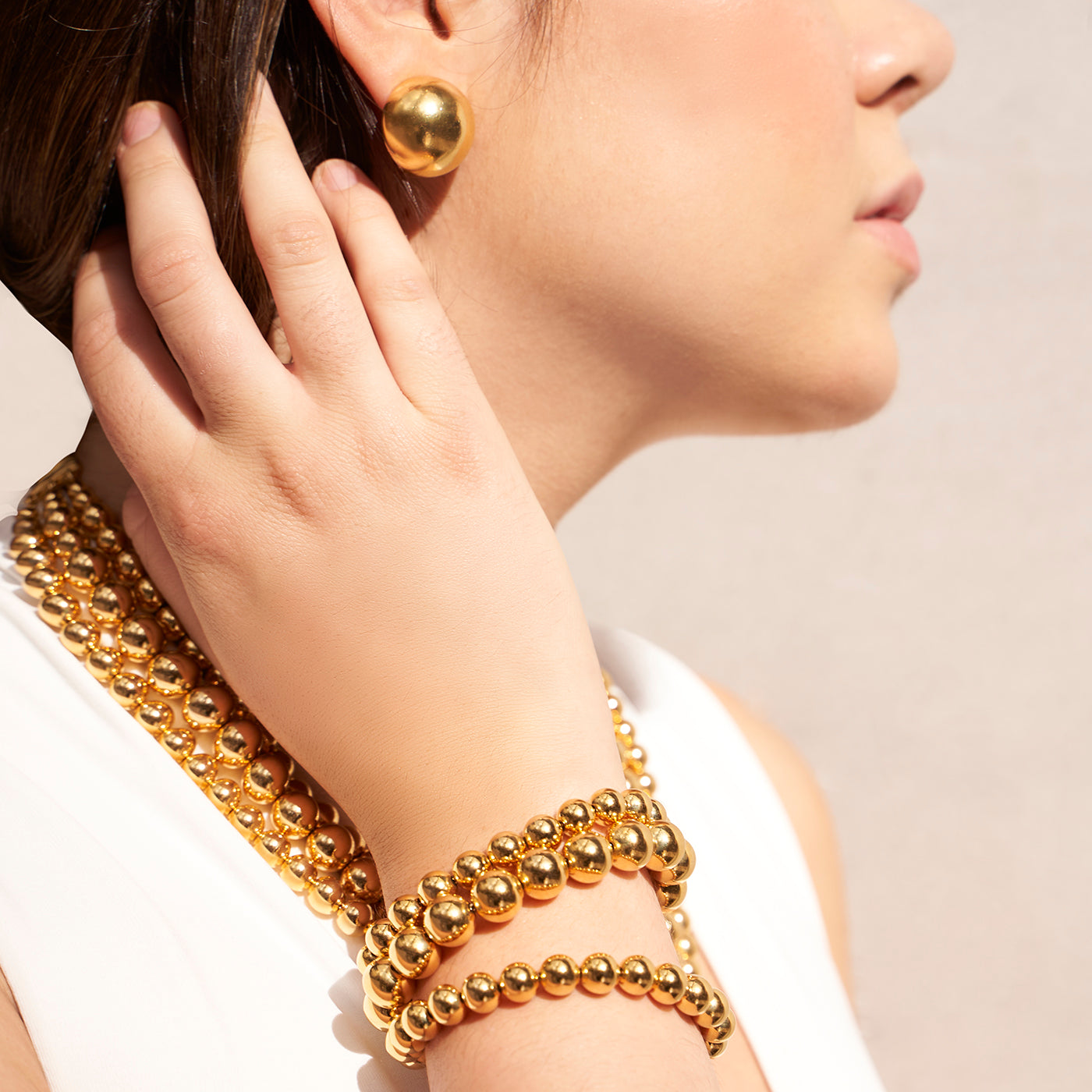 Model styled with Ben-Amun gold ball earrings, gold ball bracelet, and gold ball necklace