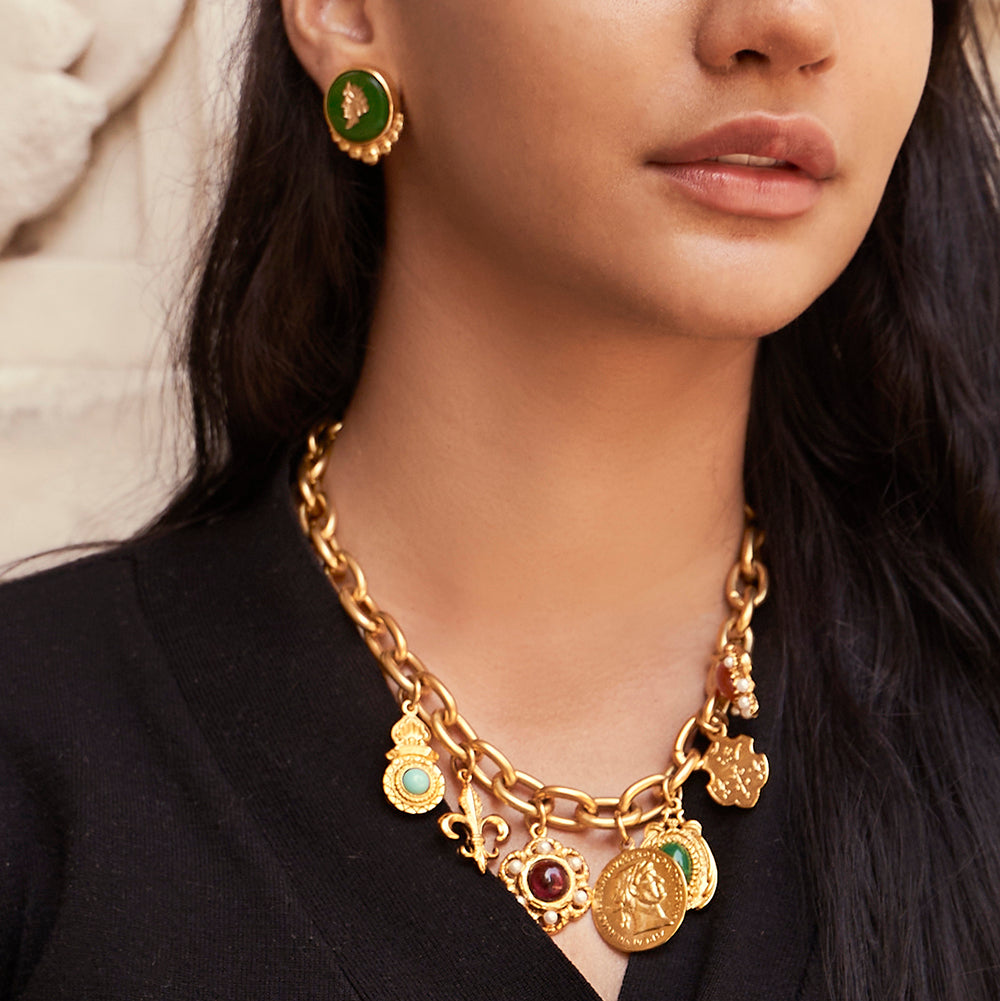model wearing gold resin cameo earrings and gold chainlink necklace with various charms