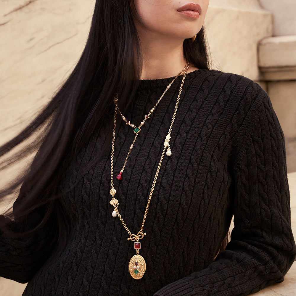 model styled with two long gold necklaces with pearls and gemstones 