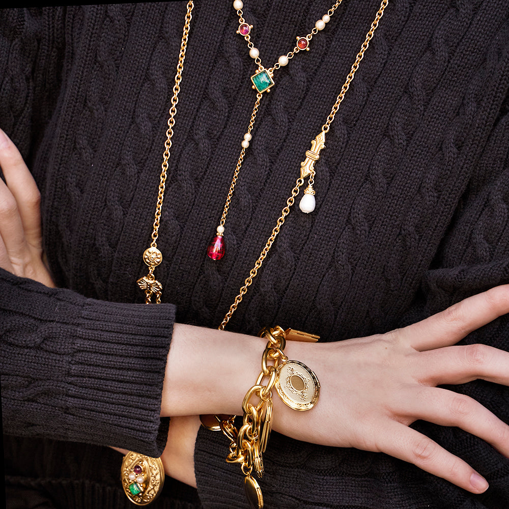 model wearing gold locket bracelet and two statement long gold drop necklaces 