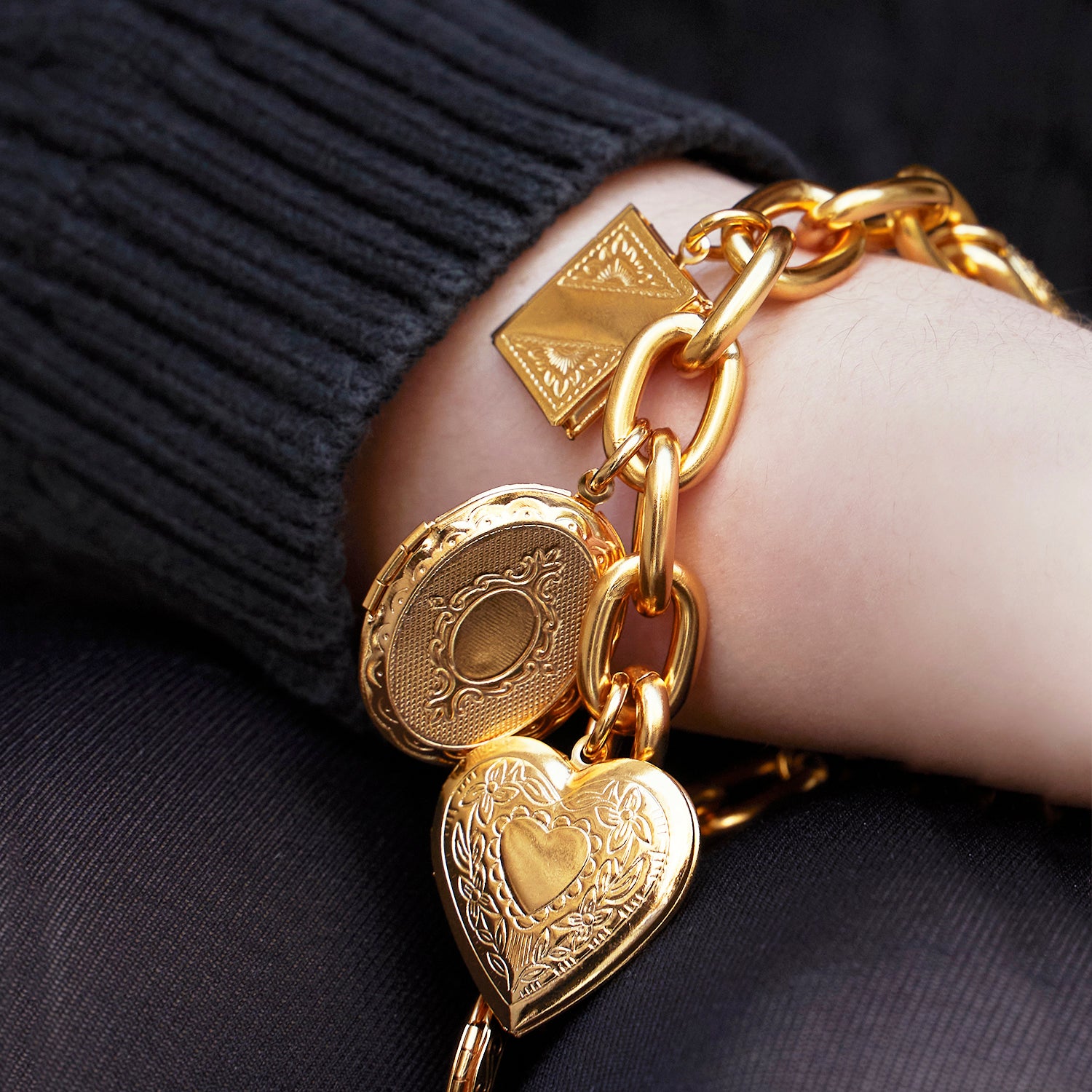 close up of chain link bracelet featuring various shaped lockets and charms 